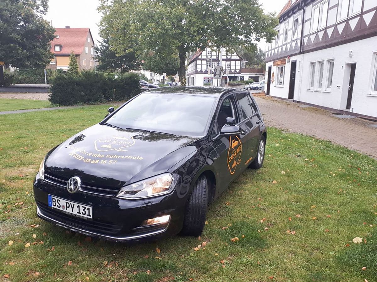 Schwarzer VW Golf der Fahrschule mit Car-&-Bike-Logo auf der Wiese — Führerscheinklasse B