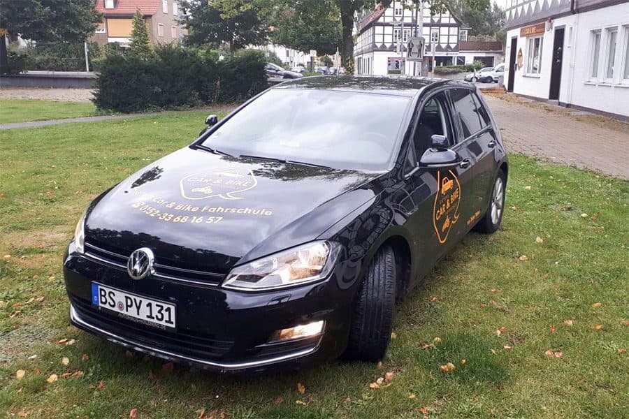 Schwarzer VW Golf der Fahrschule vor dem Fachwerkhaus